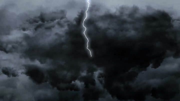 Lightning striking through dark storm clouds